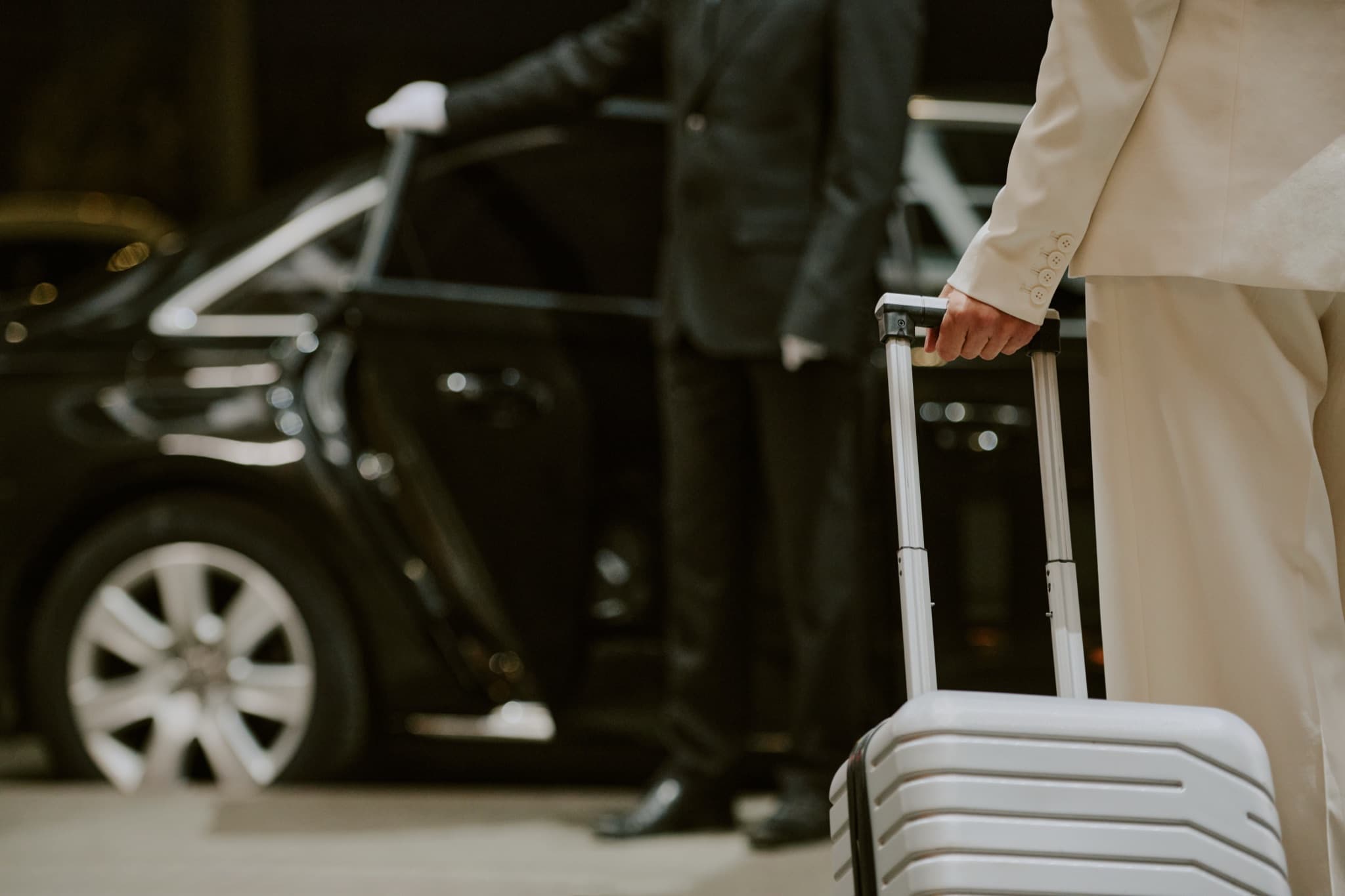 Chauffeur in a dark suit opening a car door for an arriving guest with a suitcase — private Rhodes airport transfer